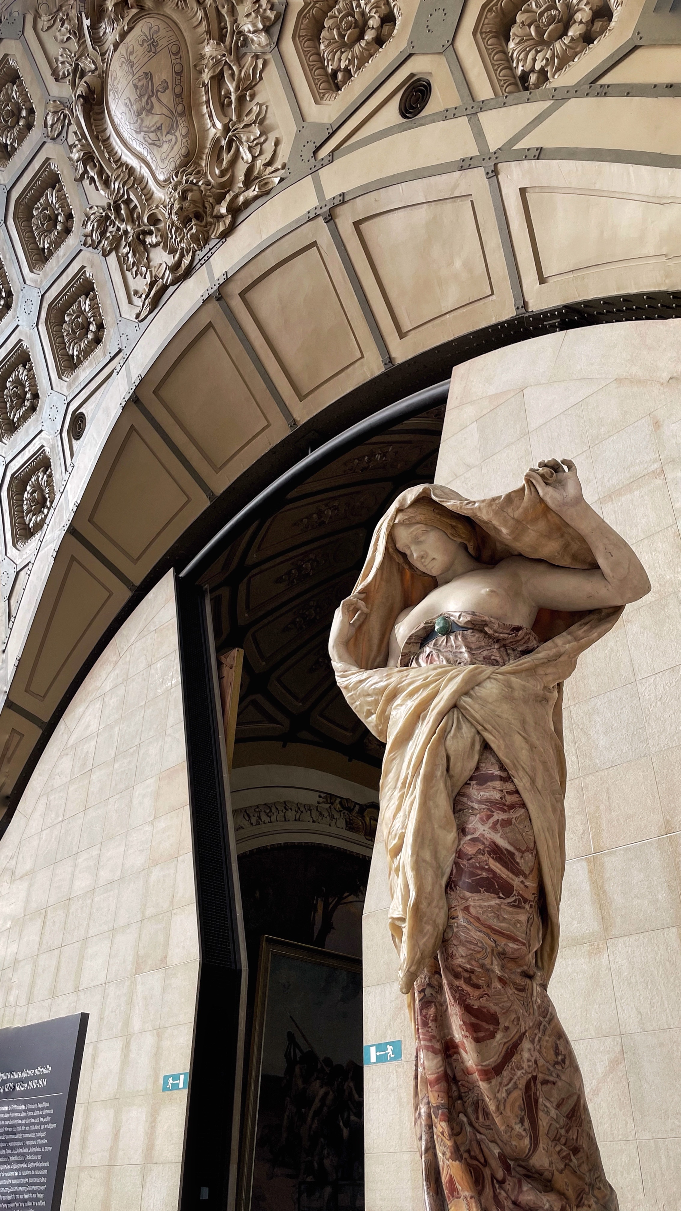Marble sculpture in drapery beneath a coffered arch